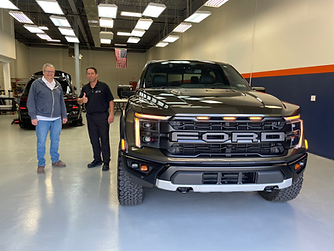 Bill, founder of Immaculate Paint Protection, smiling alongside a happy client and his freshly ceramic-coated green 2024 Ford F-150 Raptor in Allentown, PA.