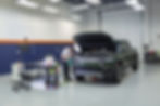 A mid-shot of Bill installing SunTek Paint Protection Film on a Rivian R1T, showcasing the entire truck within the clean and professional Immaculate Paint Protection shop.
