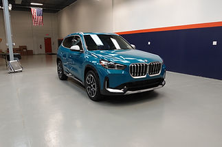 A finished BMW X1 showcasing the deep gloss and flawless finish after receiving a Full Front End SunTek Reaction PPF installation, topped with a Gyeon professional ceramic coating.