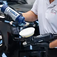 Bill priming a white Rupes foam pad with Gyeon Primer on a professional Rupes machine polisher, a critical paint correction step for a 2024 Land Rover Defender. This specific primer system refines the Santorini Black paint to ensure maximum ceramic coating adhesion.