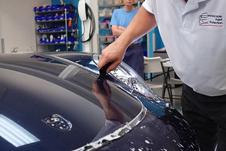 Expert installer Bill Fetter applying Paint Protection Film (PPF) to the hood of a Porsche as the client from Bethlehem, PA, looks on.