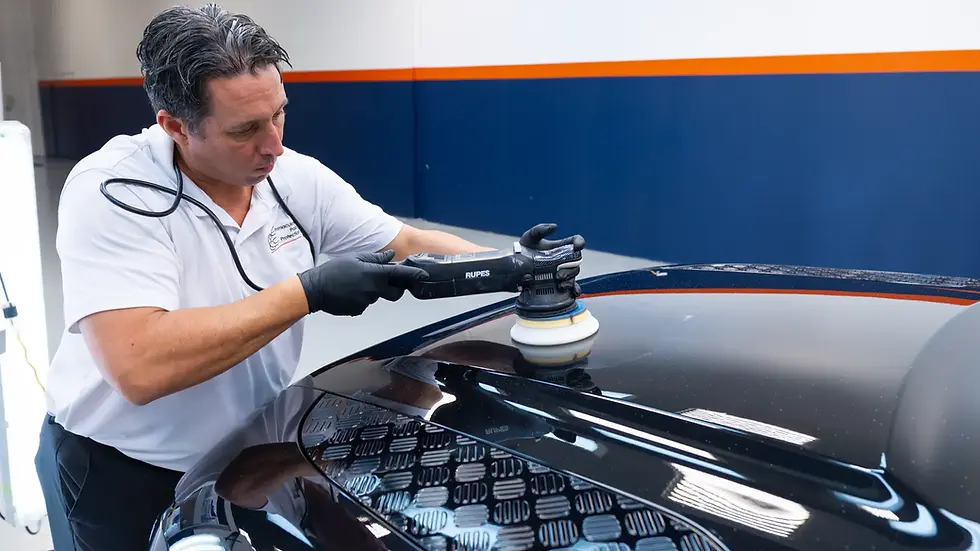 A mid-shot of Bill, a Gyeon Certified craftsman, systematically performing a multi-stage paint correction on a Santorini Black 2024 Land Rover Defender. Using a professional Rupes polisher, he is removing swirl marks and microscopic defects to create an optically perfect surface prior to the Gyeon Professional Ceramic Coating installation.