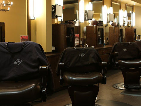 Black chairs meant for barber shop inside a barber shop, with low lighting