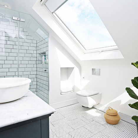 A large modern bathroom with tiled floor, walk-in-shower, marble countertop sink has been installed in a large loft conversion.
