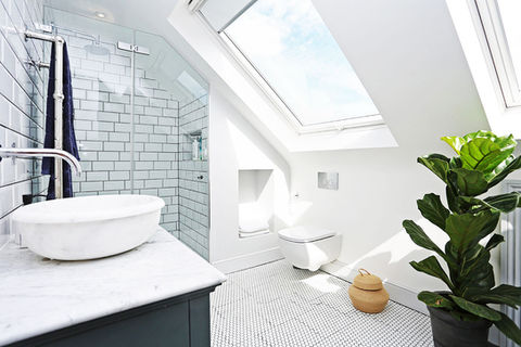 A large modern bathroom with tiled floor, walk-in-shower, marble countertop sink has been installed in a large loft conversion.
