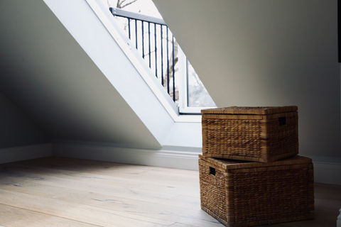 2 rectangular wicker baskets sit to the right of the shot. In the background is a large bright window balcony installed as part of a loft conversion.