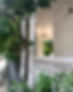 Elegant white veranda porch with Corinthian columns and stone balustrade railings next to a tree-line street.
