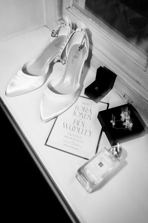 Wedding shoes and invitation styled in a flat lay, soft natural light highlighting textures and details.
