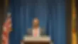 A well-dressed man in a suit and tie stands at a podium, ready to deliver a speech or presentation.