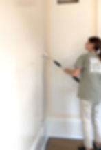 a woman painting a wall a cream white color