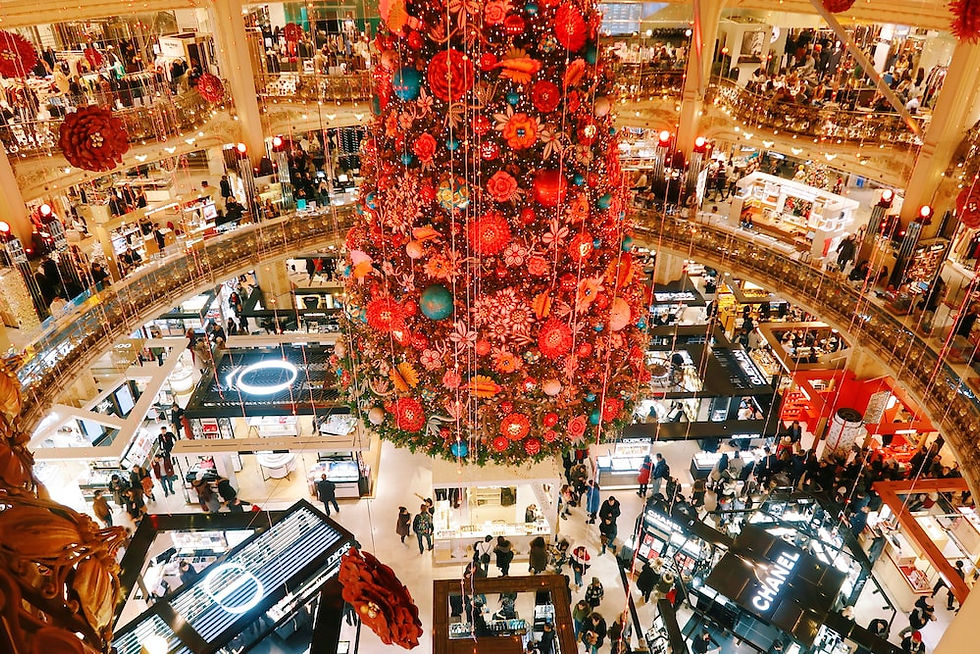  Red christmas tree hanging from mall ceiling while everyone is shopping.