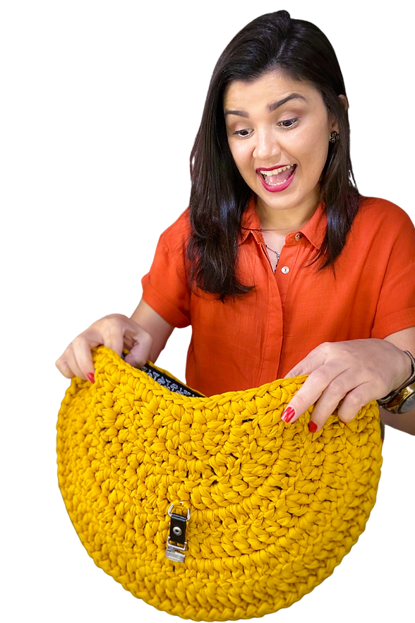 Nat olhando surpresa para dentro de uma bolsa de crochê.