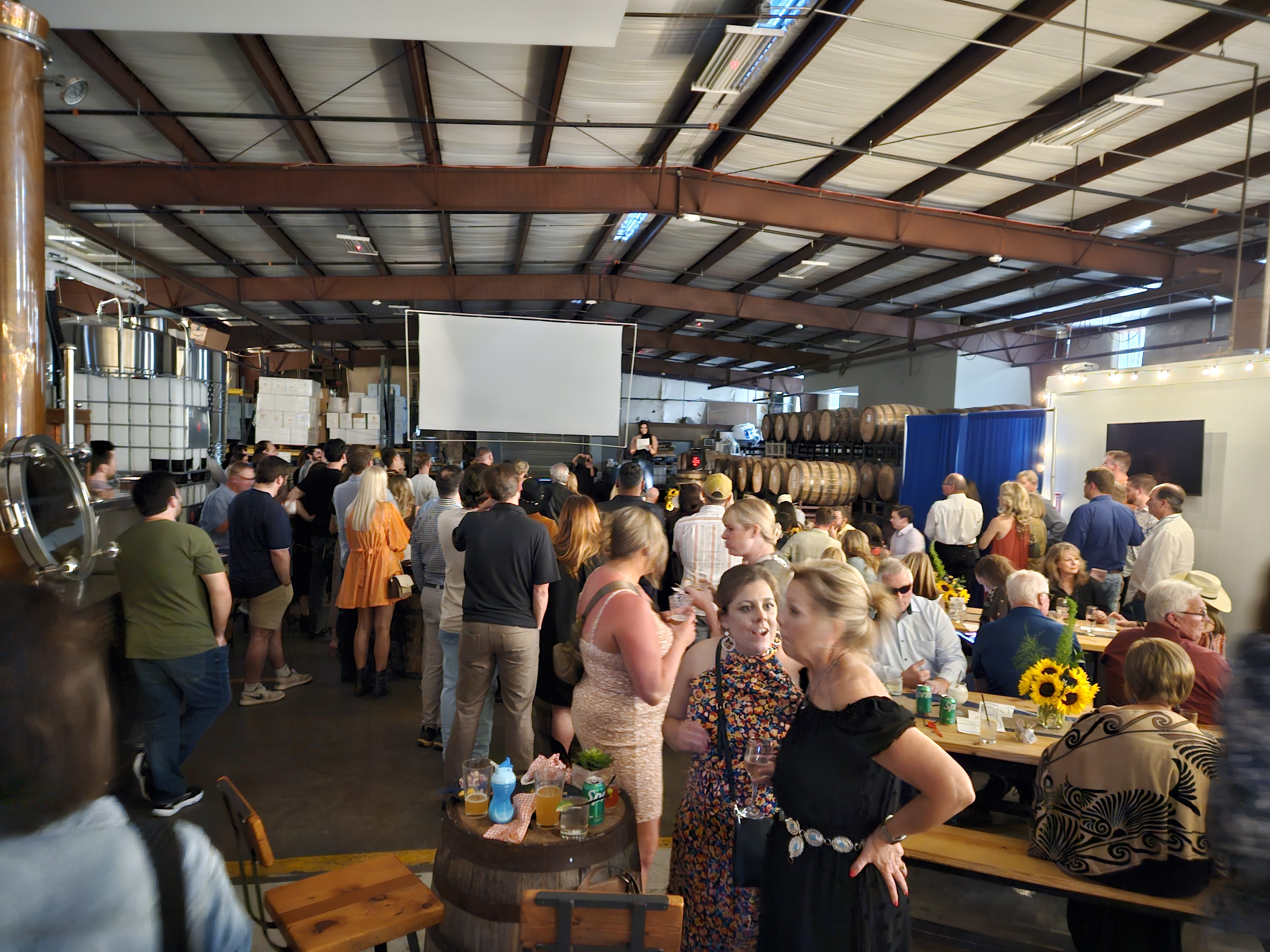 Large crowd watching a projection screen during an event at William Price Distilling in Houston.