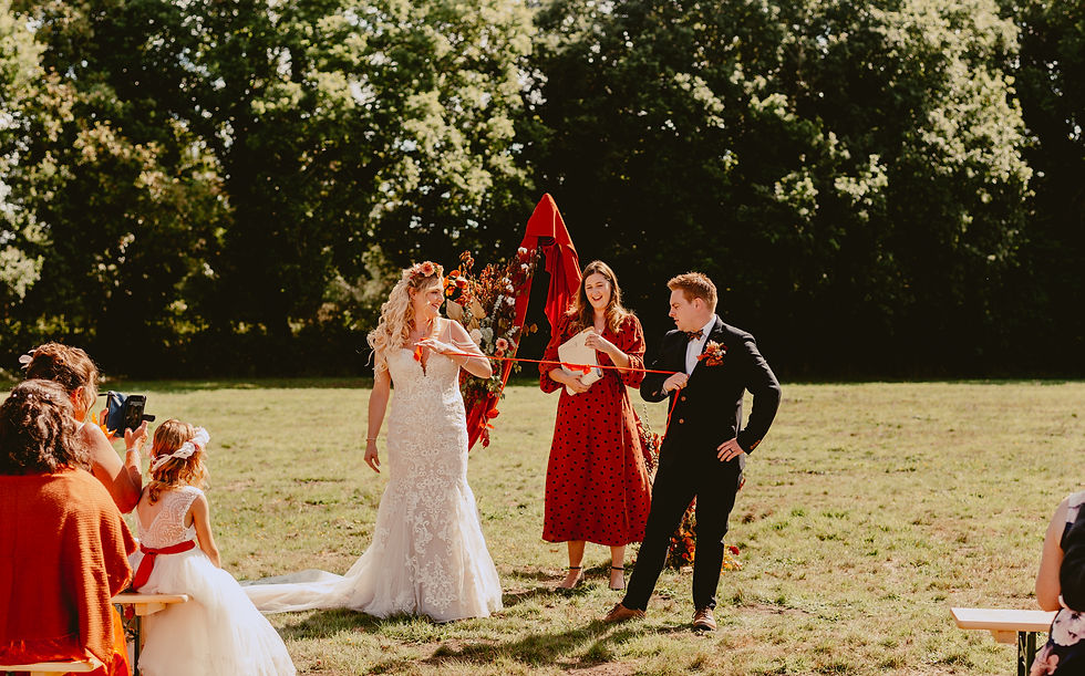 Bride and Groom pulling ribbon to tie the knot in front of Celebrant Laura Bell and ceremony display arch