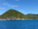 View of one of the Virgin Islands, with sailboat motoring in front.