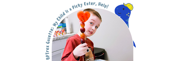 A boy holding a fruit cabob with grapes and a slice of watermelon cut in the shape of a heart.