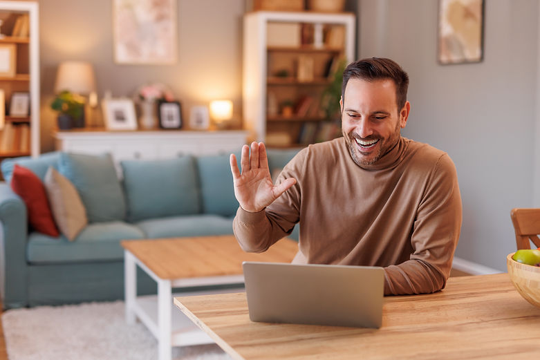 cheerful-mid-adult-businessman-waving-hand-laptop-while-attending-online-meeting-home-offi