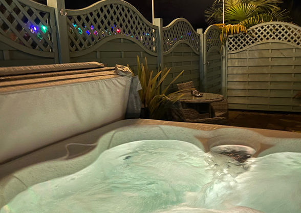 The private hot tub at Palm View Lodge sits just outside the lodge on its own sheltered decking, with soft evening lighting that creates a calm, relaxing space to unwind.