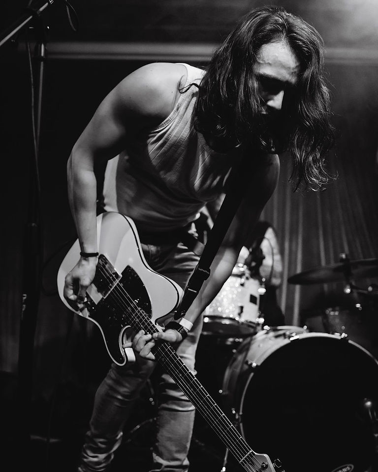 Male musician playing electric guitar on stage during a concert performance.