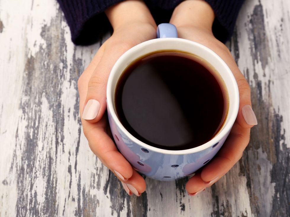 A woman's hand holding a cup of newly brewed organic coffee.