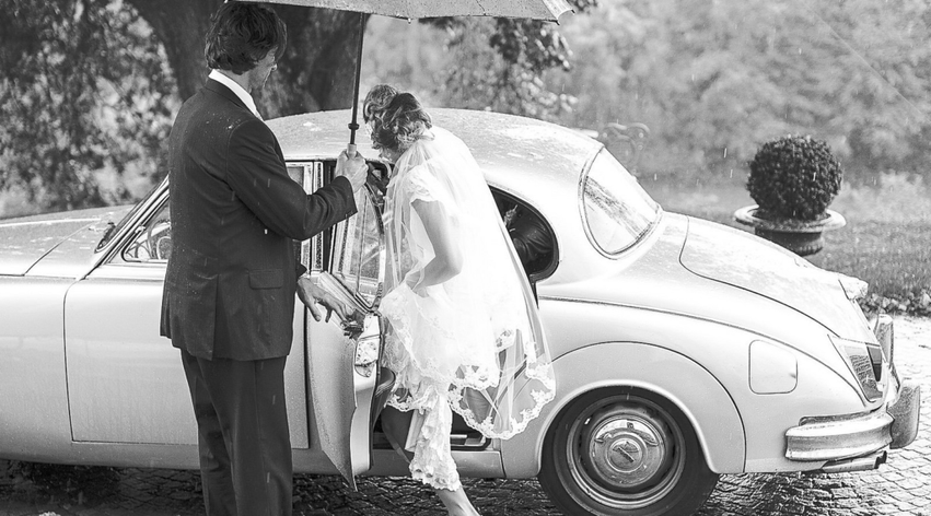 Das Brautpaar steigt in ein stilvolles Hochzeitsauto ein – Vintage trifft auf Eleganz.