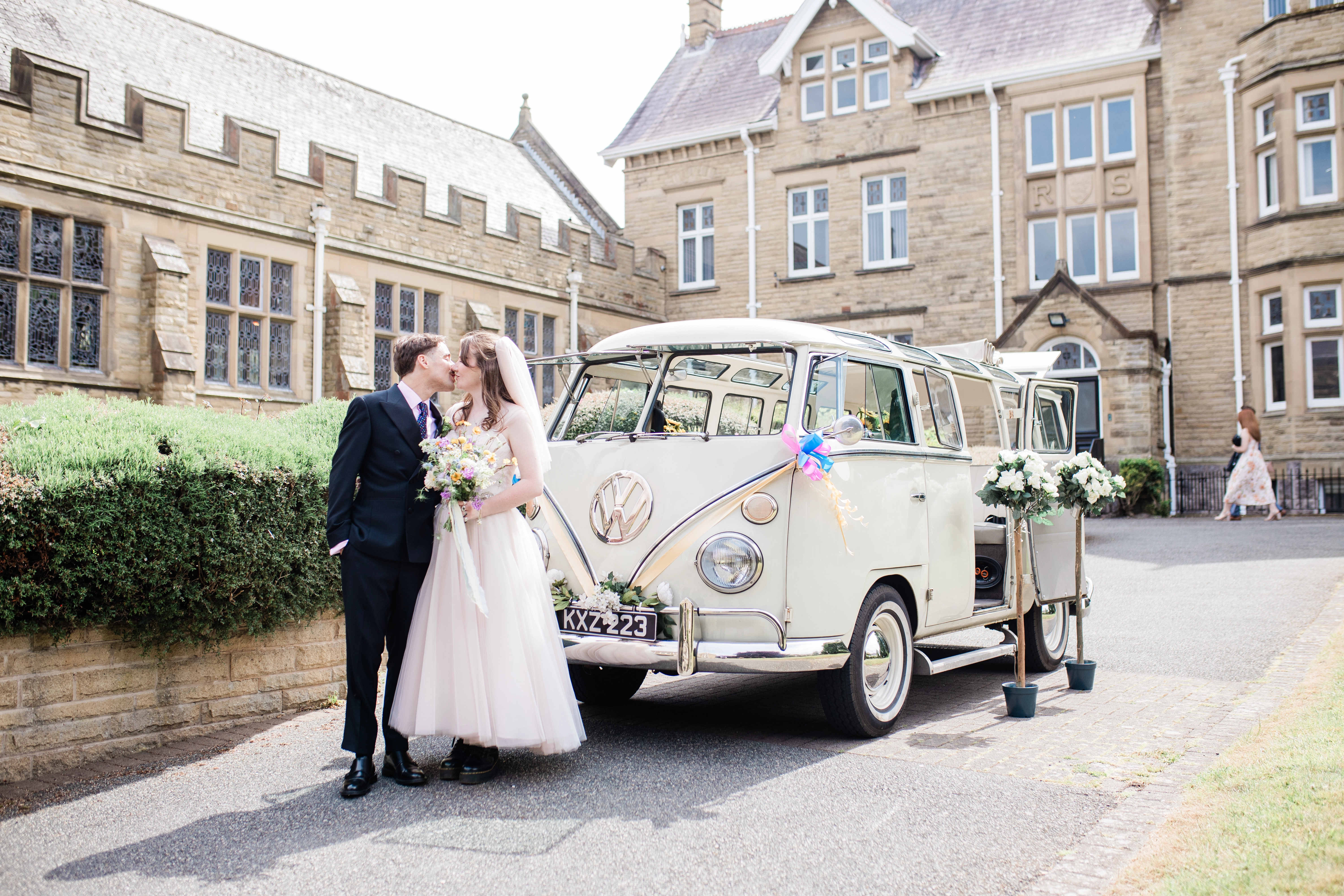 The bride and groom kissing outside of the VW Camper