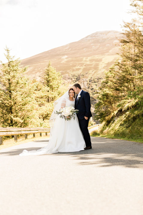 Newlywed couple on a scenic mountain road during sunset