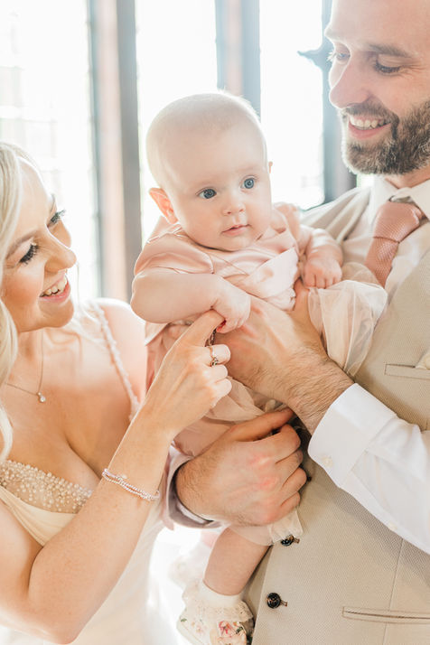 Smiling parents holding their baby at a wedding