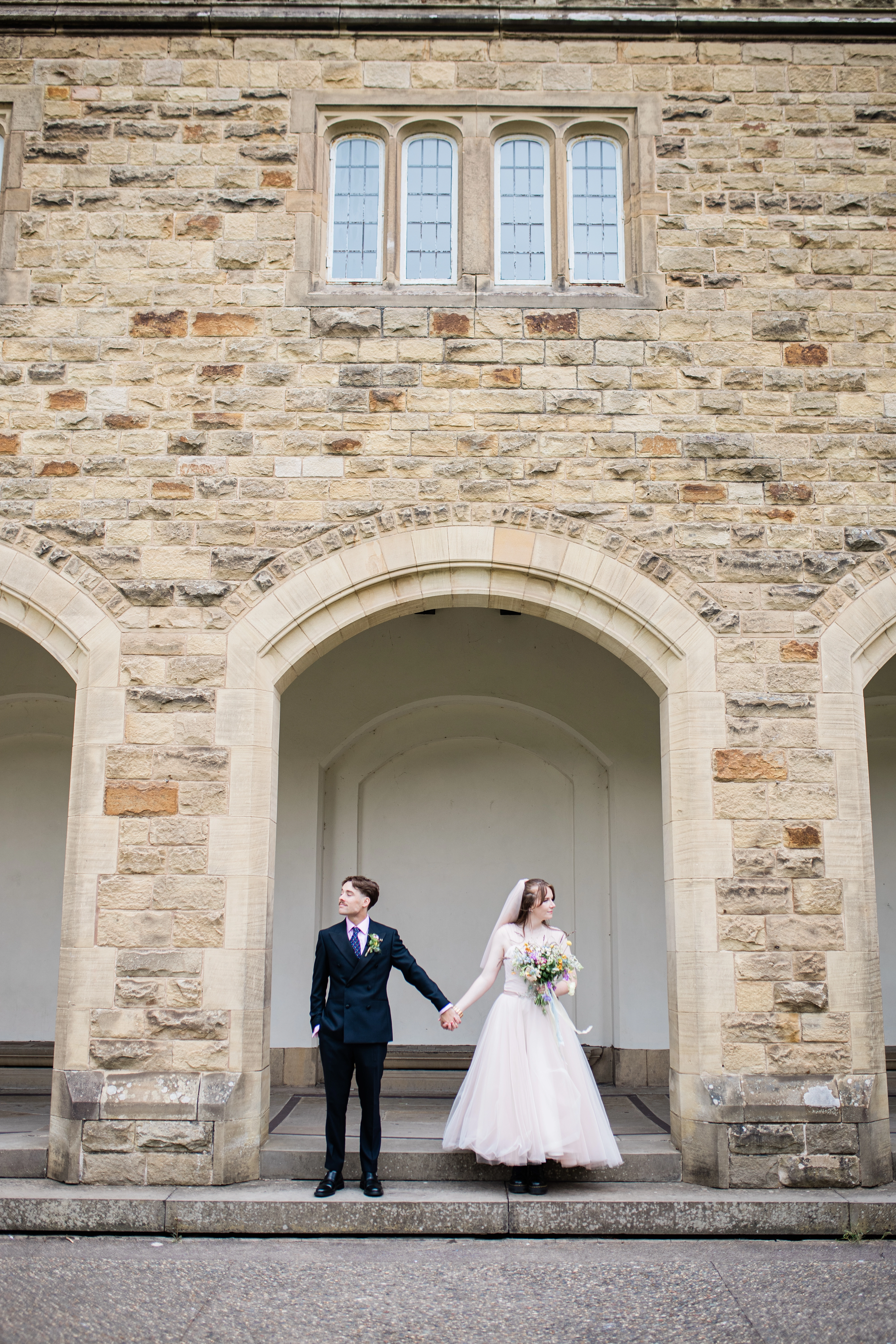 the bride and groom under an archway holding hands