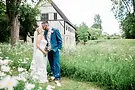Newlyweds kissing in a wildflower field with historic building.