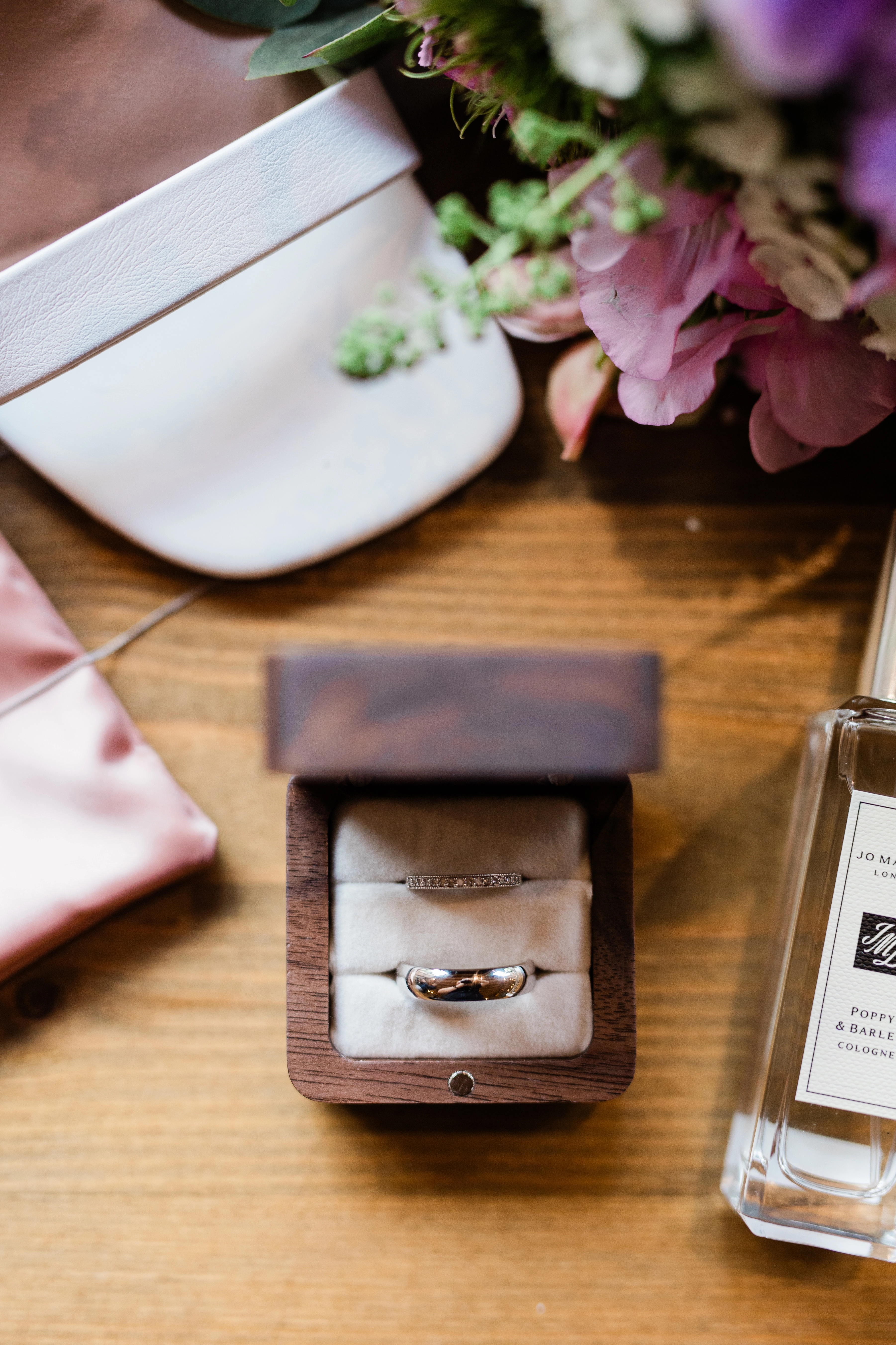 wedding flatlay including rings, shoes, perfume and flowers