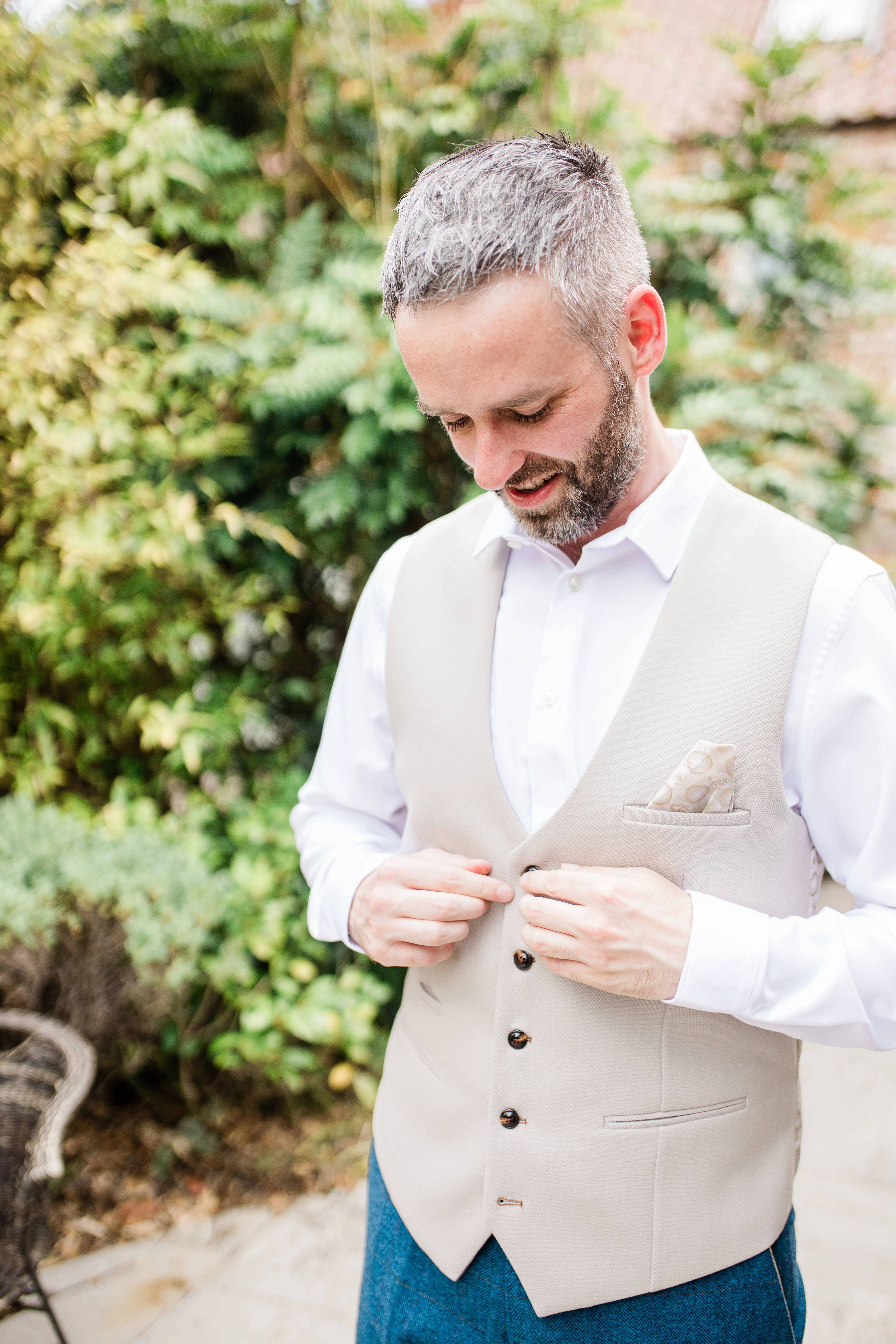 The groom doing up his waistcoat