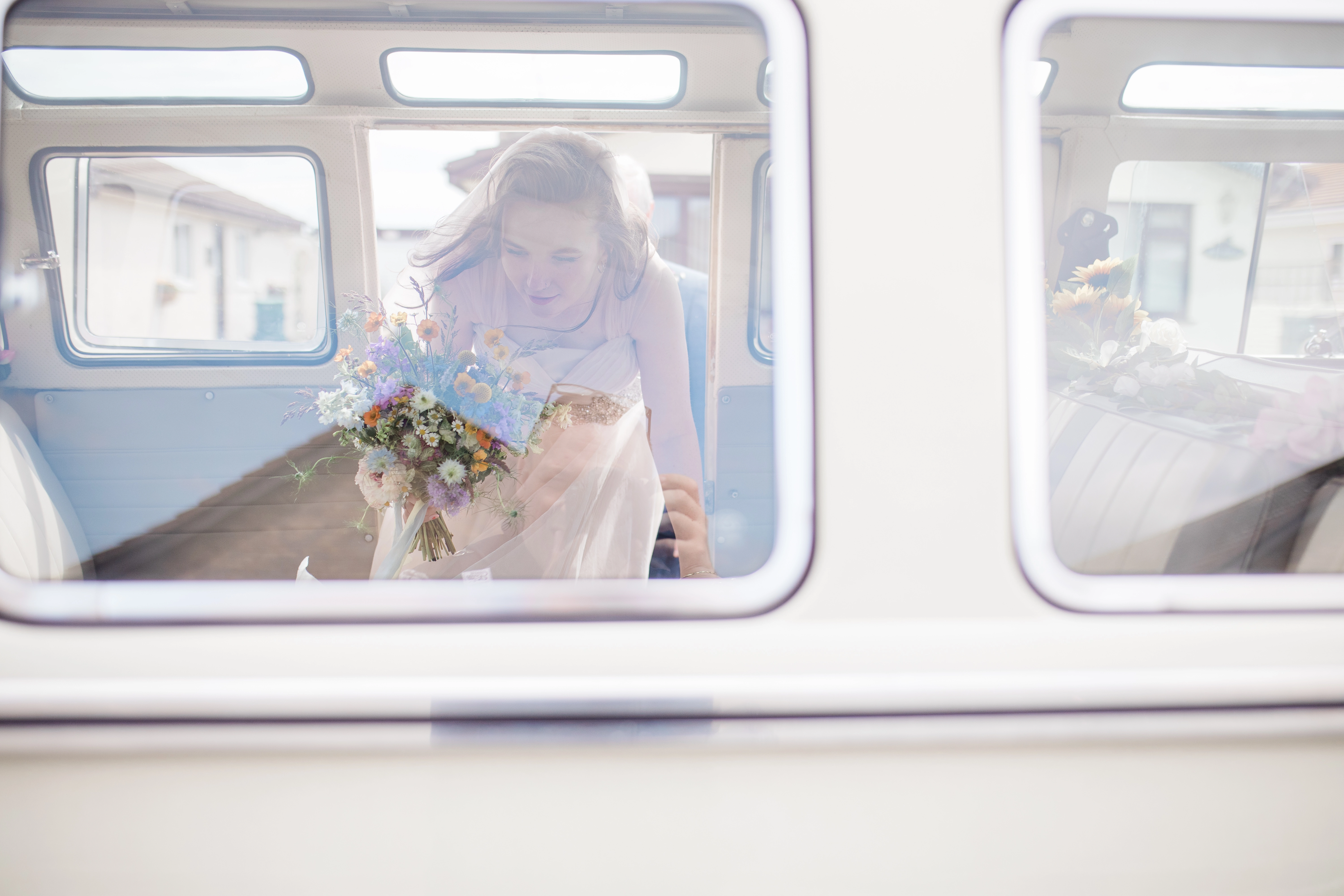 A bride getting into a VW Camper to take her to her wedding