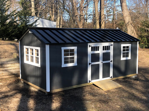 Dark gray shed with a black roof and white trim.