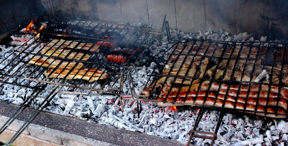 Grilled meats and botifarra sausage on the barbecue as part a calçotada in Barcelona