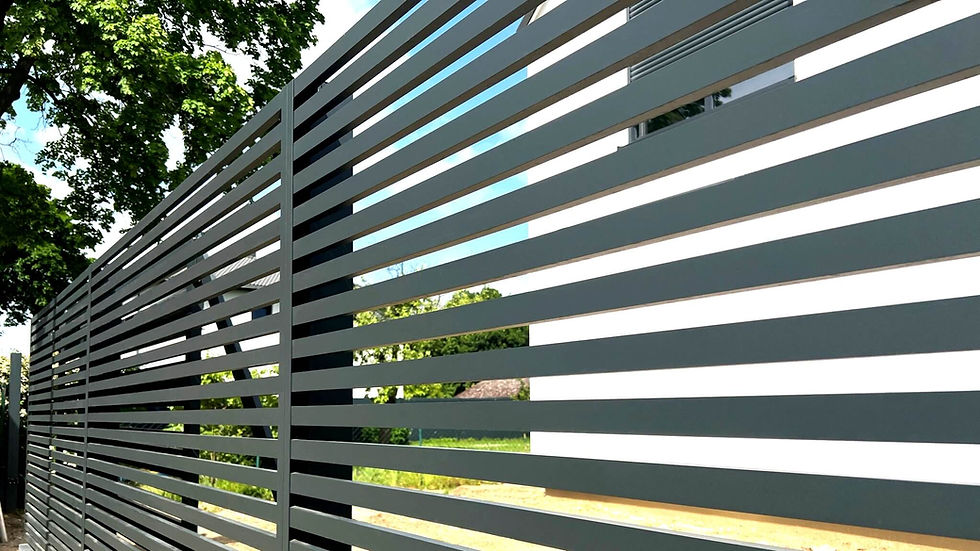 Im Vordergrund ein modernes Aluminiumzaunsystem in Anthrazit, im Hintergrund ein Garten mit einem Baum und einem Haus.