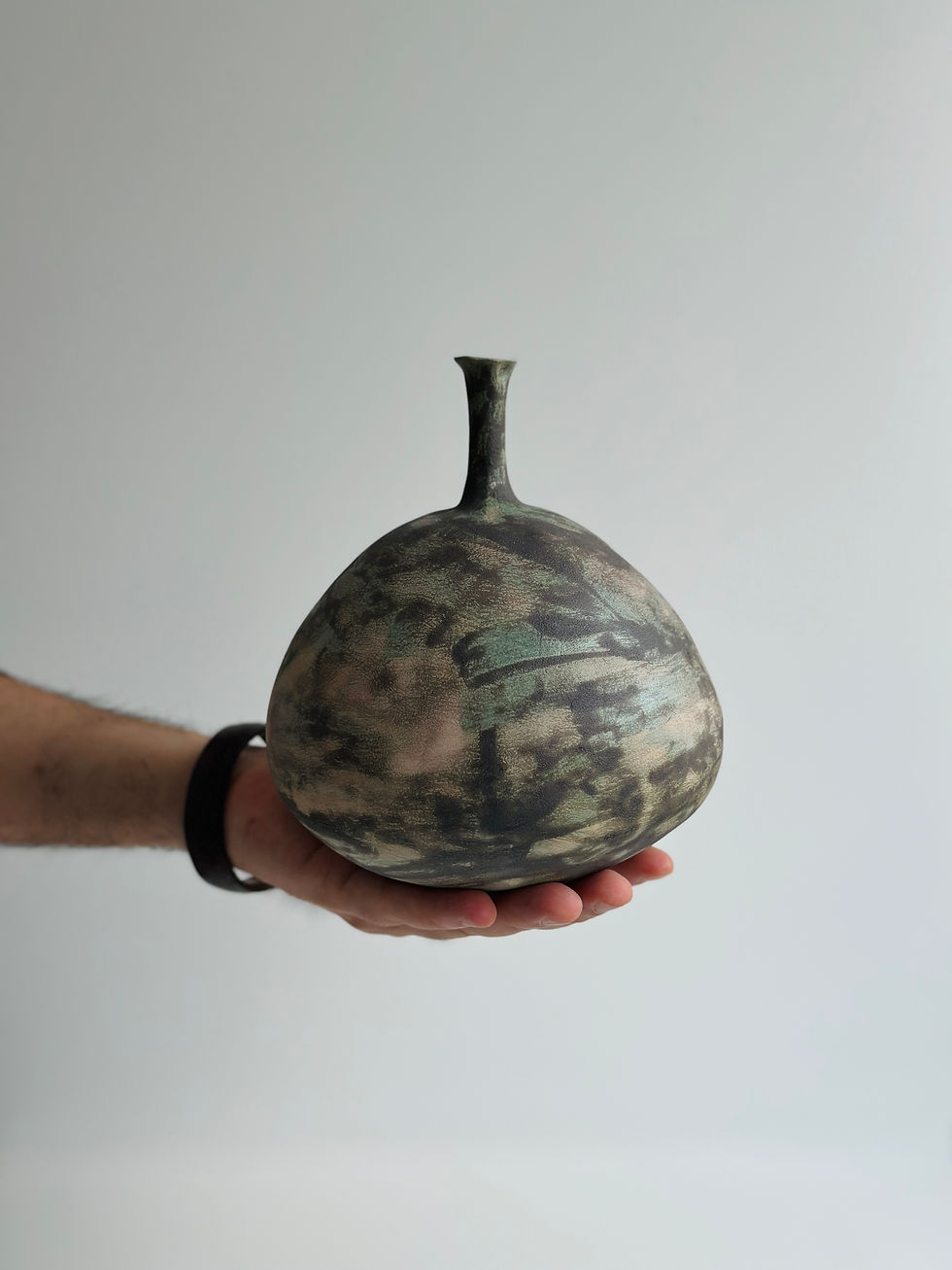 Hand holding a unique dark ceramic vase Memory Vessel 0034 with interesting textures and patterns