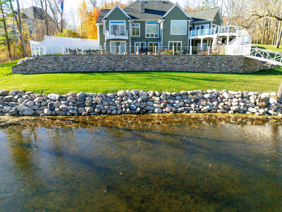 Stone seawall with landscaping along backyard pond in Grand Ledge