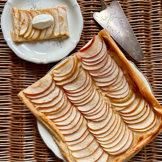 Apple tart and a slice served on a plate with a dollop of creme fraiche