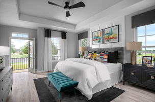 A modern bedroom with a gray upholstered bed, colorful pillows, vibrant wall art, black-and-white curtains, a teal tufted bench, and a balcony view.