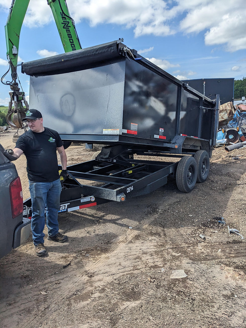 Worker standing by a trailer for junk removal services.