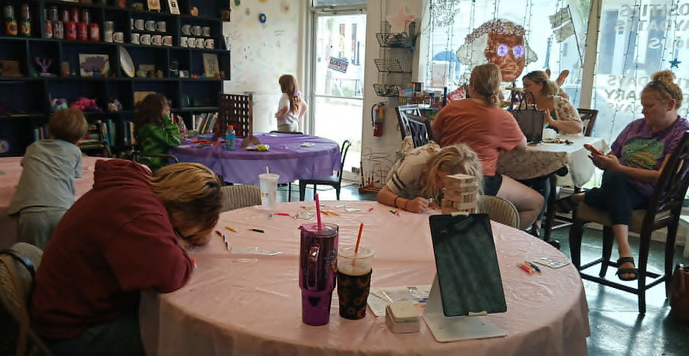 Children and adults craft and color at round tables inside Happy Hippie Customs.
