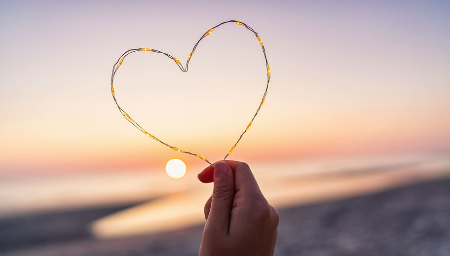 womand-holding-heart-shape-made-led-lights-beach-sunset.jpg