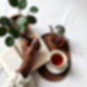 A black woman hand holding a pen, A journal, , and tea setup near a plant Mood_ Mystical.
