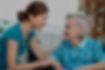 Caregiver smiling at elderly woman in wheelchair