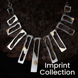 Imprint silver necklace on dark wood.