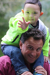 A boy with Down syndrome sits on his dads shoulders