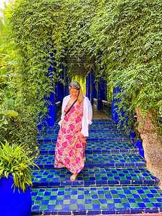 A photo of a woman in a pink dress surrounded by leaves going down blue stairs