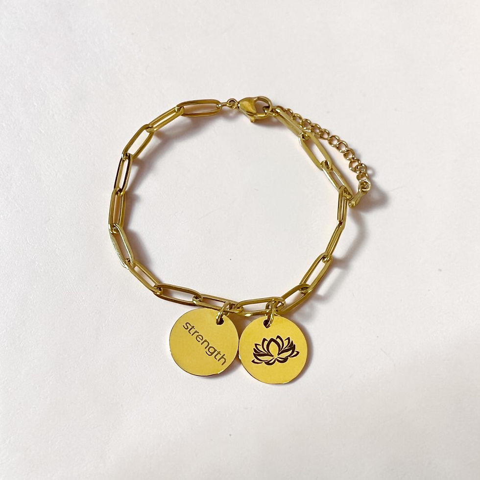 Thumbnail: gold grow through it charm bracelet with lotus and strength  charms over head view