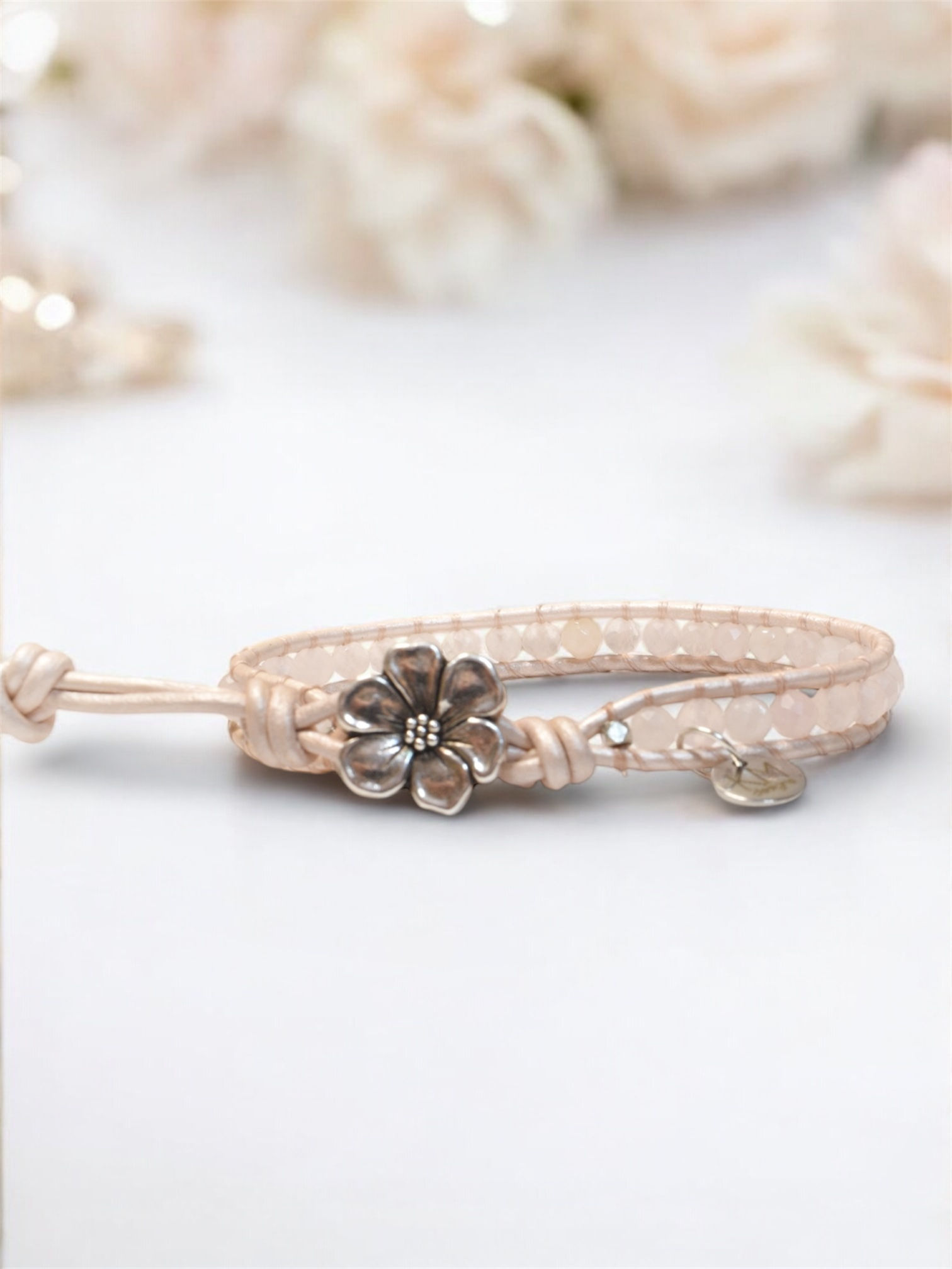 pink rose quartz leather wrap bracelet with silver flower button, floral background